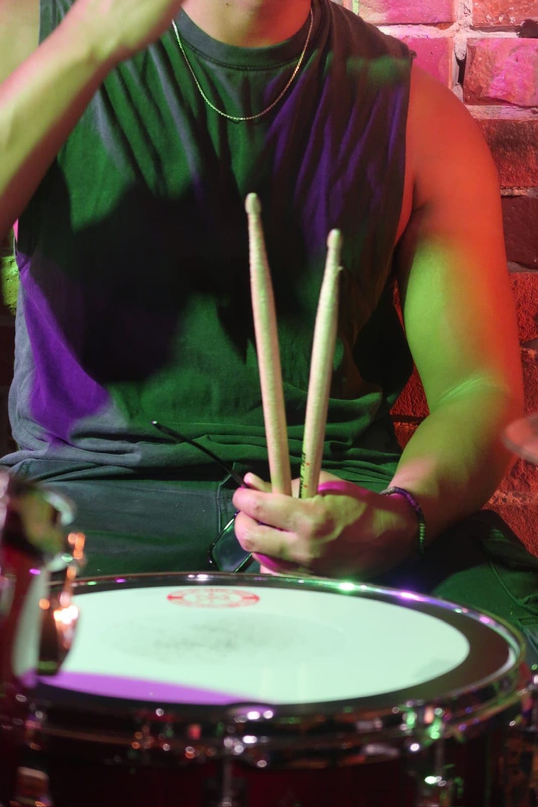Drummer gripping sticks over the snare between hits