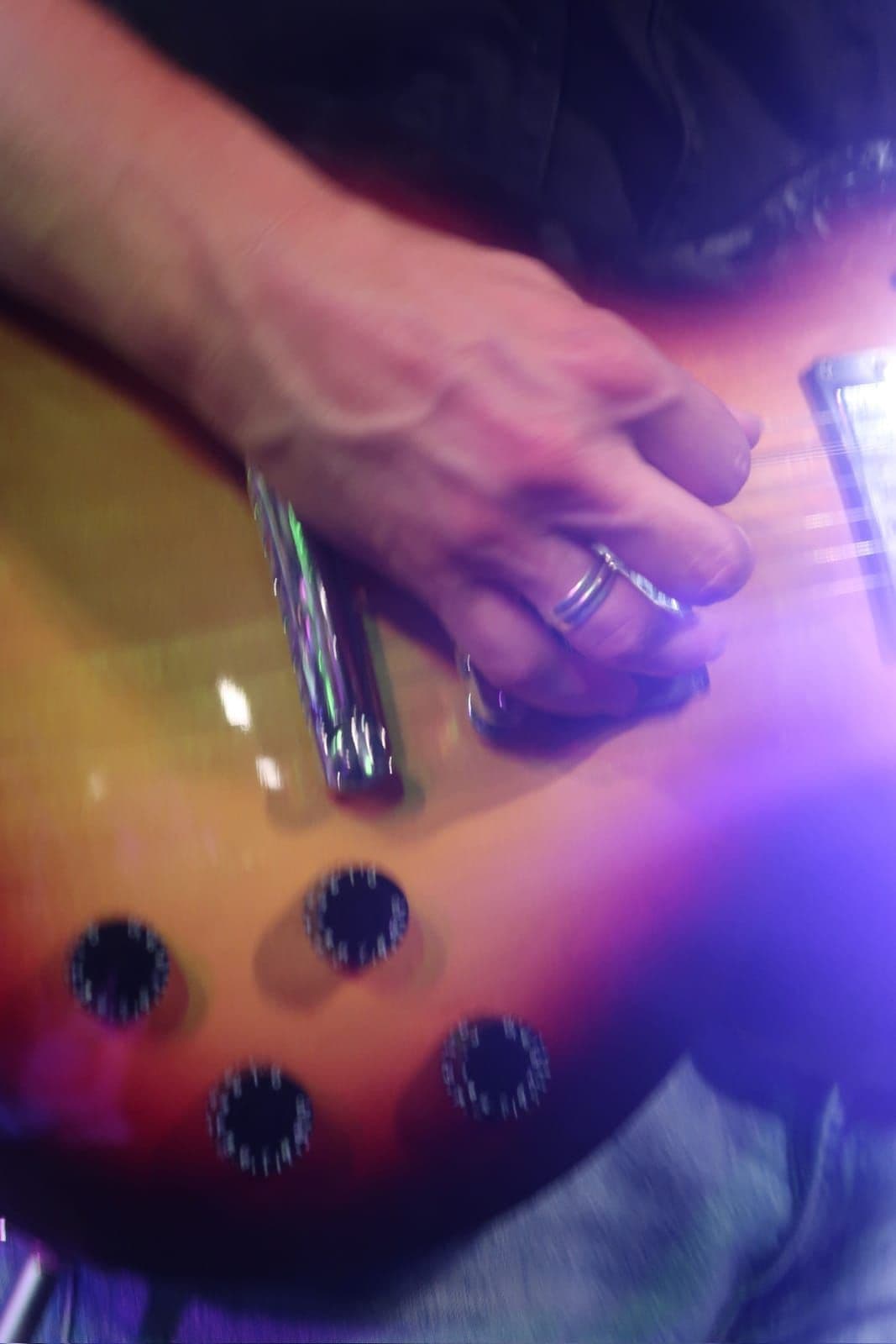 Close-up of a guitarist's fretting hand under stage light