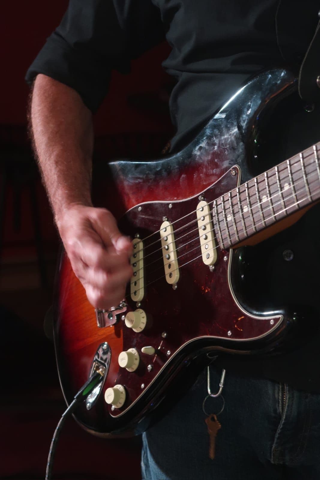 Close-up of a guitarist's strumming hand on a sunburst Stratocaster